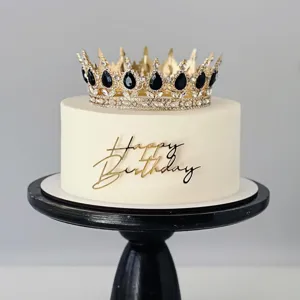 Gros plan détaillé de la décoration de gâteau Happy Birthday en acrylique doré et couronne.