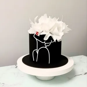 Elegant minimalist black cake detail view with artistic face line art and white floral decor.