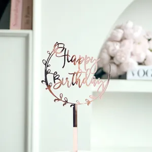 Gros plan sur le topper de gâteau d'anniversaire en acrylique or rose avec détail floral.