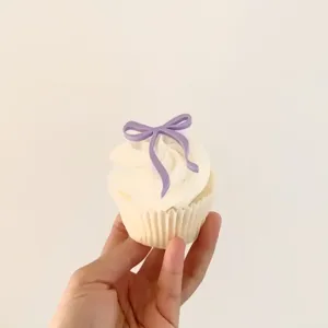 Detail shot of a purple acrylic bow cupcake topper, perfect for party and birthday decoration.