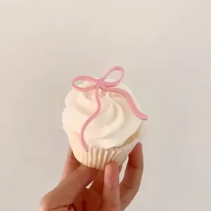 Closeup of a pink acrylic bow cake topper, perfect for birthday and party baking decoration.