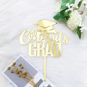 Nahaufnahme Detail des goldenen Acryl Abschluss Kuchenaufsatzes mit Congrats Grad Motiv.