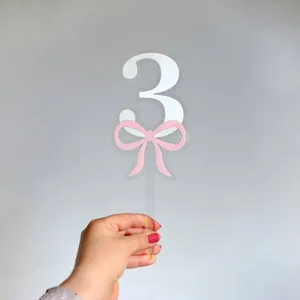 Clear acrylic number 3 cake topper with pink bow design for birthday party cake decoration.