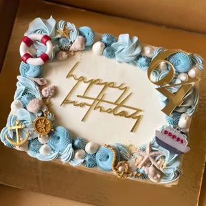 Torta de cumpleaños temática oceánica con crema azul, adornos de acrílico dorado y marinos.