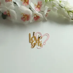 Detailaufnahme des goldenen Acryl Love You Kuchendekors mit rosafarbenem Herz für Partys.