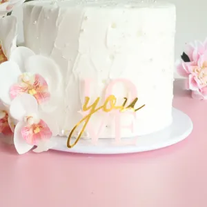 Nahaufnahme des rosa-goldenen Acryl Kuchenaufsteckers mit Liebe Aufschrift auf Torte.