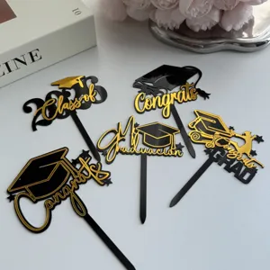 Detail view of black and gold acrylic graduation cake toppers 2026 party supplies.