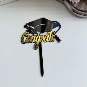 Black and gold acrylic graduation cake topper with Congrats lettering for party decor.