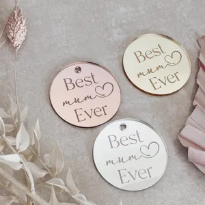 Close-up details of round acrylic cake topper charms with engraved Best mum Ever text.