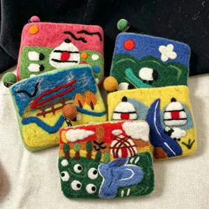 Handmade wool felt coin purse detail showing colorful landscape yurt and cute sheep embroidery.