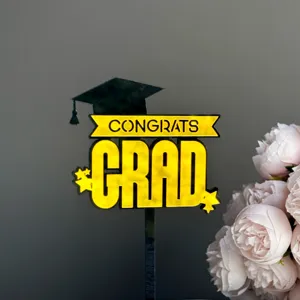 Detail view of gold and black acrylic graduation cake topper with grad cap and stars.