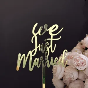Primer plano de un adorno de tarta de acrílico dorado con la elegante frase 'We Just Married'.
