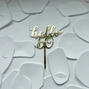 Gold acrylic hello 50 cake topper detail view, stylish party decoration for birthday celebration.