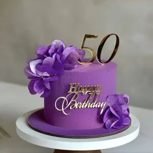 Gros plan détaillé d'un gâteau d'anniversaire violet luxueux avec des décorations dorées en acrylique.