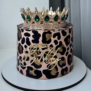 Gedetailleerde close-up van een gouden acryl Happy Birthday taarttopper en elegante kroon.