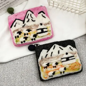 Handmade wool felt coin purse detail showing cute mountain and sheep embroidery design with zipper.
