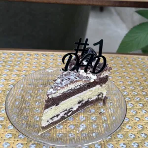 Detailed close-up of a black #1 dad cake topper placed on a delicious layered slice cake.