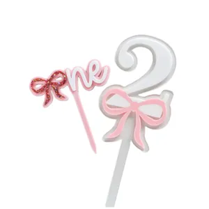 Acrylic birthday cake topper set with bow and number design for sweet party decor.