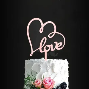 Detailed close-up shot of pink acrylic love heart cake topper displayed on a sweet dessert cake.