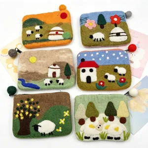 Handmade wool felt coin purse detail showing cute sheep and pastoral landscape patterns.