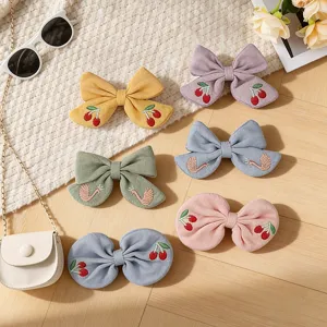 Cotton linen fabric hair clips detail view featuring cute embroidered bow and swan designs.