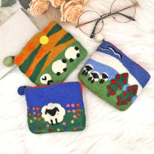 Detailed view of handmade wool felt coin purse featuring cute sheep and sunset designs.