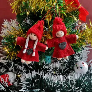 Detailed shot of cute red knitted Christmas doll ornaments hanging on a festive tree.