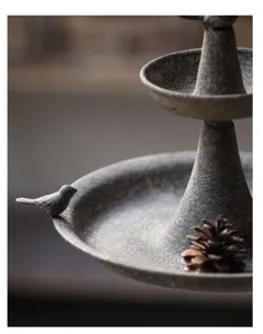Vintage rustic concrete bird feeder detail shot, multi-tier garden decor display.