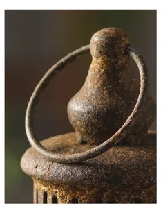 Close-up detail shot of vintage rusted iron candle lantern top with hanging ring texture.