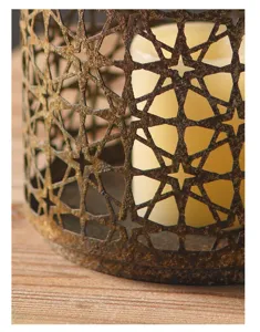 Close-up detail of vintage retro distressed iron candle holder with geometric star hollow design.