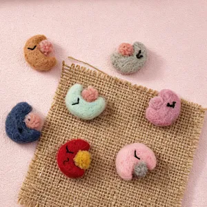 Cute wool felt crescent moon accessories with cute sleeping faces and soft pom-poms for diy crafts.