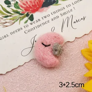 Cute pink wool felt moon charm with grey star accent, detailed handmade craft accessory.