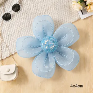 Close-up detail of light blue organza five-petal flower accessory with glitter center.