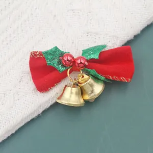 Close-up detail van een rode fluwelen kerststrik met gouden metalen belletjes en groene bladeren.