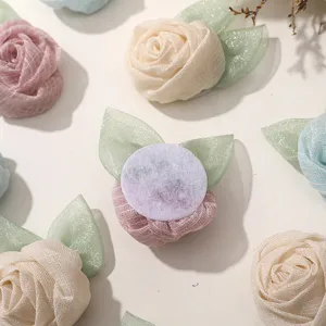 Mesh rose flower garment accessory detail showing fabric petals and glitter leaves close-up.