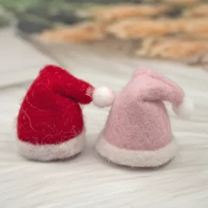 Close-up detail of mini felt Christmas hats, red and pink wool hat DIY craft decoration.