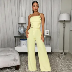 Detail shot of the yellow camisole top and wide leg pants set with metal button accents.