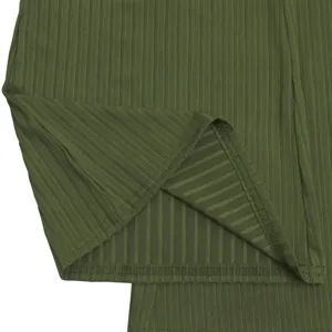Close-up detail of dark green ribbed fabric jumpsuit hem showcasing fine texture and stitching.