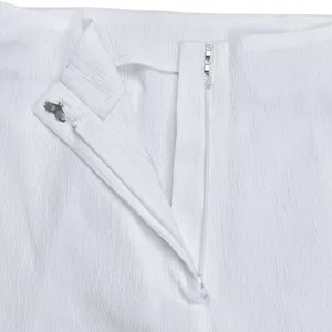 Detail view of women's solid pleated trousers, featuring zipper and metal hook closure.