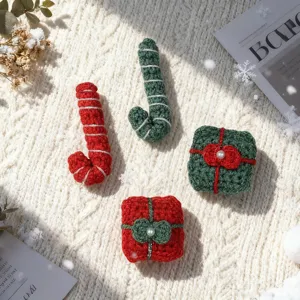 Close-up detail of Christmas crochet candy cane and gift box festive holiday knit accessories.