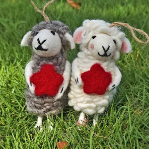 Handmade wool felt sheep hanging ornament holding red star, cute craft detail shot for decor.