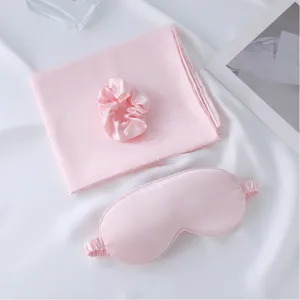Pink satin sleep set including eye mask, scrunchie, and pillowcase for comfortable sleeping.