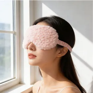 Primo piano di una morbida maschera da notte in peluche rosa vicino a una finestra luminosa.