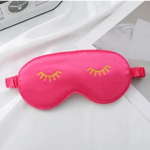 Pink silk sleep mask with cute yellow eyelash print for comfortable sleeping and travel rest.