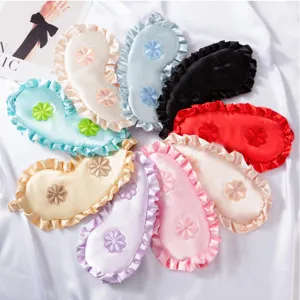 Detalle de antifaces de seda multicolores para dormir con volantes y flores bordadas.