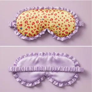 Detailed close-up view of silk satin sleep mask featuring purple ruffle trim and leopard pattern.