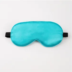 Close-up detail of a smooth turquoise silk sleep mask with black elastic strap for comfort.