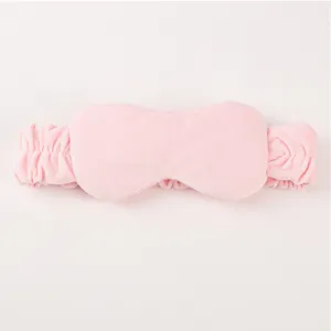 Close-up detail of the pink plush 2-in-1 sleep mask and hair band, soft velvet texture.