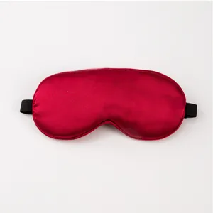 Close-up detail of smooth red silk sleep mask with black elastic strap for sleep.