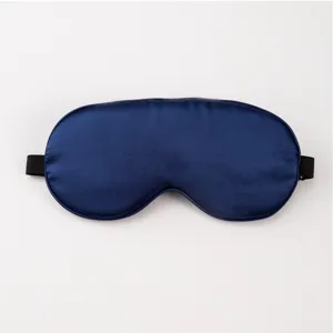 Close-up detail of dark blue silk sleep eye mask, smooth satin texture and elastic band.